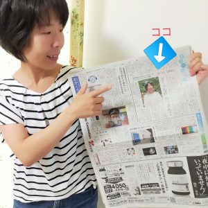 新聞を掲げる女性の画像